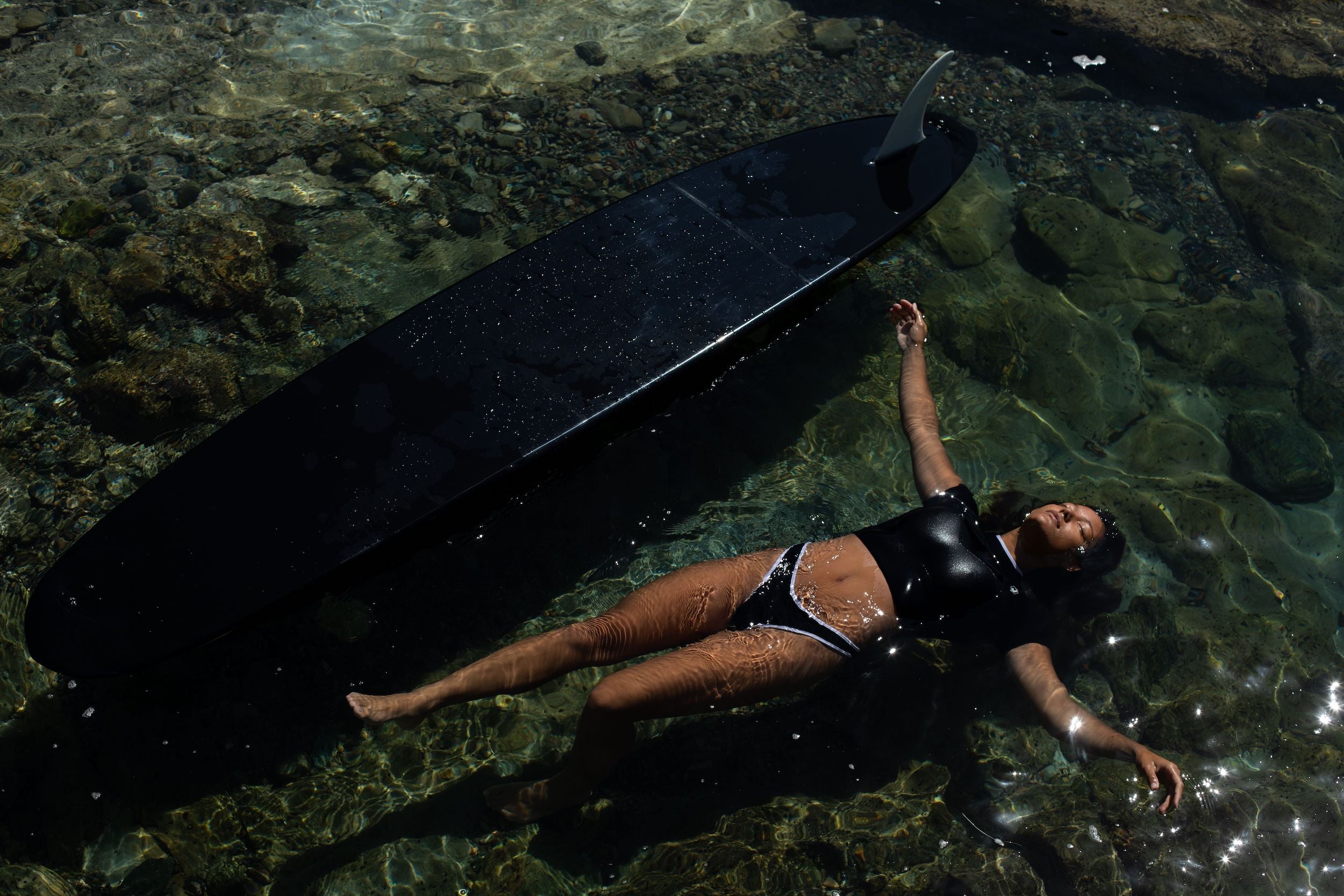 woman laying on back in water in custom wetsuit